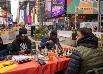 توندي أوناكويا، في الوسط، بطل الشطرنج النيجيري والمدافع عن تعليم الأطفال، يلعب لعبة الشطرنج في تايمز سكوير، الجمعة 19 أبريل 2024، في نيويورك.  (صورة AP/يوكي إيوامورا)