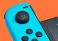 صورة مقربة لوحدة تحكم Nintendo Joy-Con زرقاء على خلفية برتقالية.