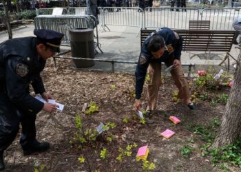 ضباط الشرطة يجمعون المنشورات التي أسقطها الشخص الذي أضرم النار في نفسه.  الصورة: رويترز